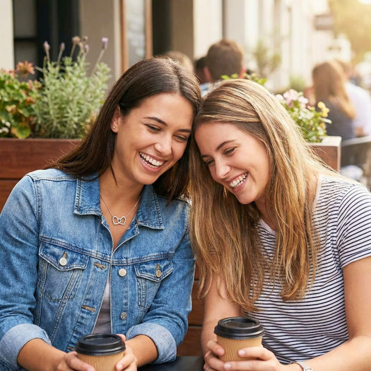 Two best friends laughing hysterically over coffee, wearing denim jackets, representing a close friendship bond.
