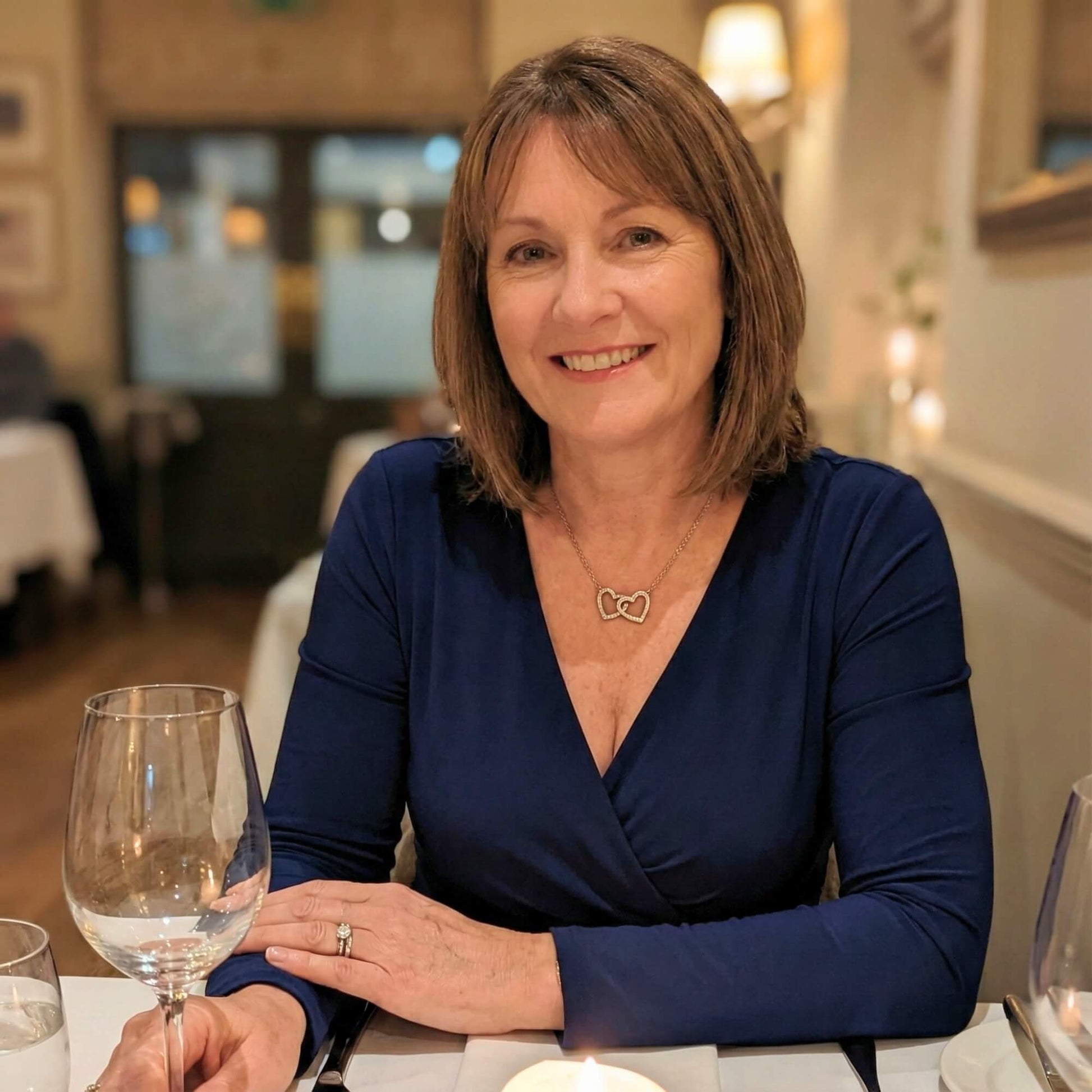 Mature wife wearing the white gold anniversary necklace during a romantic dinner date.