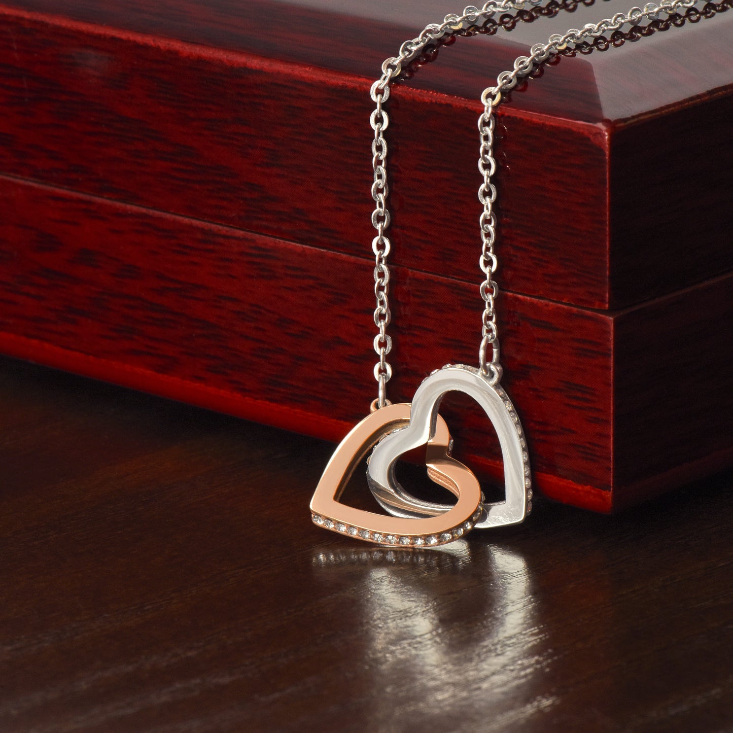Necklace with a heart-shaped interlocking pendant on a wooden mahogany surface
