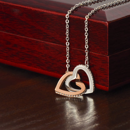 Necklace with a heart-shaped interlocking pendant on a wooden mahogany surface